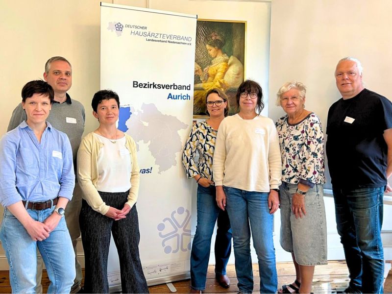 Der neue siebenköpfige Vorstand steht im Tagungshotel vor dem Rollup des Bezirksverbandes Aurich.